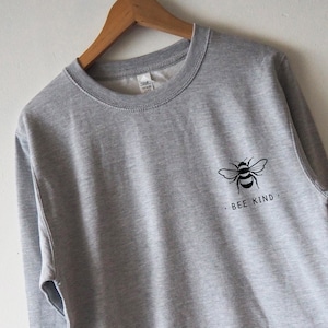 May include: A gray sweatshirt with a black bee graphic and the text "BEE KIND" on the front.