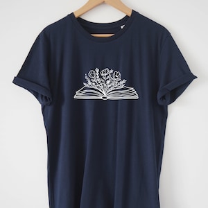 May include: A navy blue t-shirt with a white graphic of an open book with flowers growing out of it.