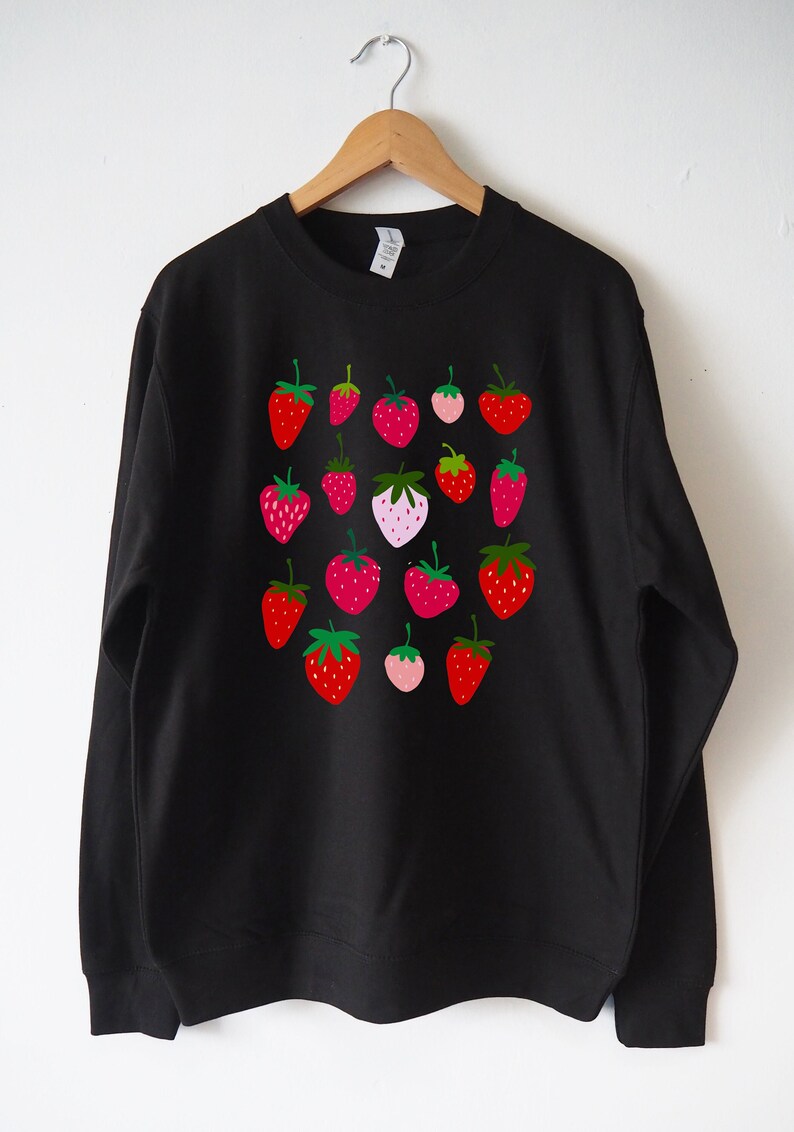 May include: Black sweatshirt with a colourful strawberry print. The strawberries are red, pink and green.
