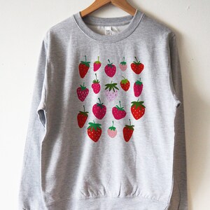 May include: A grey sweatshirt with a pattern of red and pink strawberries printed on the front.