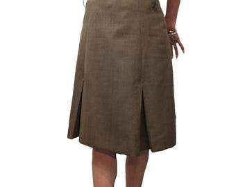 Op de afbeelding: Een bruine knielange rok met een brede tailleband en plooien. De rok is gemaakt van een textuurstof en heeft een getailleerde pasvorm. Het model draagt zwarte hakken en een crèmekleurige blouse.