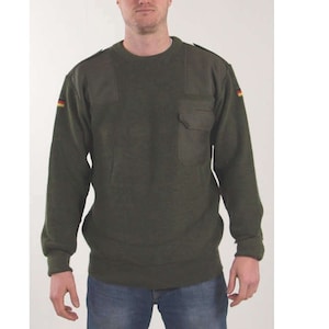 May include: An olive green crew neck sweater with a chest pocket and shoulder epaulettes. The German flag is visible on the left shoulder. The sweater is made of a thick, durable material.