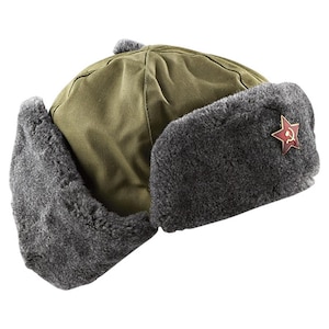 Könnte beinhalten: Eine olivgrüne Ushanka-Mütze mit grauen Kunstfell-Ohrenklappen. Ein rotes Sternemblem mit Hammer und Sichel ist an der Seite befestigt. Die Mütze hat eine abgerundete Oberseite und einen kleinen grauen Bommel.