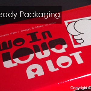 May include: Red gift box with a white design that says "Two In Love A Lot" and a cartoon image of two people hugging. The box is ready for gift-giving.