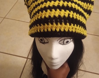 May include: A handmade crochet hat with cat ears, featuring alternating horizontal stripes of yellow and black. The hat is displayed on a mannequin head with black hair.