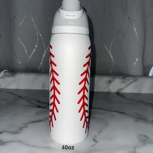 Puede incluir: Botella de agua blanca de 1,18 litros con dise&ntilde;o de costura de b&eacute;isbol roja. La botella tiene una tapa gris con un mecanismo de apertura de bot&oacute;n. El texto "Lift to Unlock" est&aacute; impreso en la tapa.