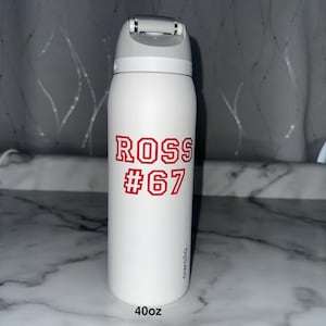 Puede incluir: Botella de agua aislada blanca con tapa abatible gris. La botella presenta el nombre "ROSS" y el n&uacute;mero "67" en letras rojas. La botella est&aacute; etiquetada como "40oz", que equivale a aproximadamente 1,18 litros.