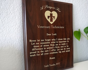 Puede incluir: Una placa de madera marrón con una inscripción dorada que dice "A Prayer For Veterinary Technicians". La inscripción incluye un corazón con una cruz y dos siluetas de animales. El texto continúa con una oración para los técnicos veterinarios, terminando con "Amen" y "Faith Tanaka, RVT".