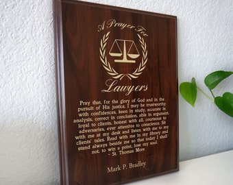May include: A wooden plaque with a dark brown finish, featuring the text "A Prayer For Lawyers" in gold lettering. The plaque includes a prayer and the name "Mark P. Bradley".
