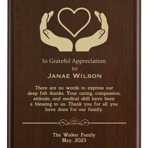 May include: A brown wooden plaque with a gold heart and hands design. The text reads "In Grateful Appreciation to JANAE WILSON There are no words to express our deep felt thanks. Your caring, compassion, attitude, and medical skill have been a blessing to us. Thank you for all you have done for our family. The Walker Family May, 2023"