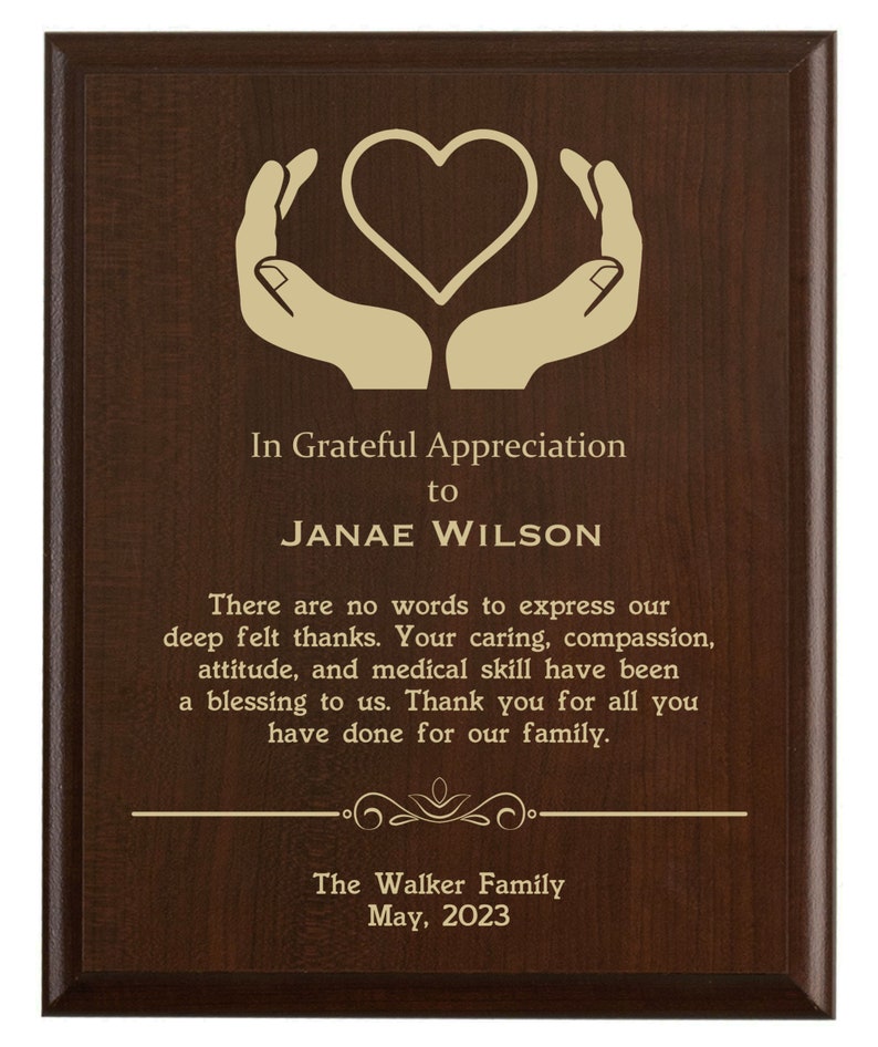 May include: A brown wooden plaque with a gold heart and hands design. The text reads "In Grateful Appreciation to JANAE WILSON There are no words to express our deep felt thanks. Your caring, compassion, attitude, and medical skill have been a blessing to us. Thank you for all you have done for our family. The Walker Family May, 2023"