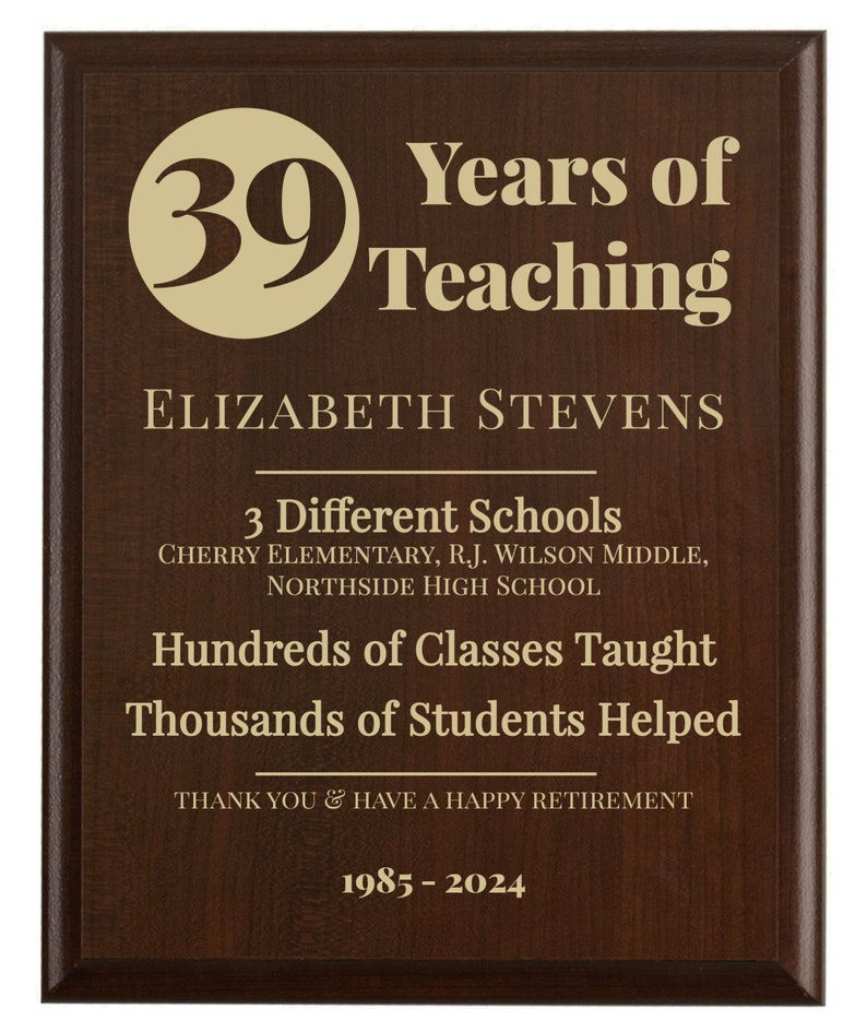 May include: A brown plaque with gold lettering celebrating 39 years of teaching. The plaque reads "Years of Teaching", "Elizabeth Stevens", "3 Different Schools", "Cherry Elementary, R.J. Wilson Middle, Northside High School", "Hundreds of Classes Taught", "Thousands of Students Helped", "Thank You & Have a Happy Retirement", and "1985-2024".
