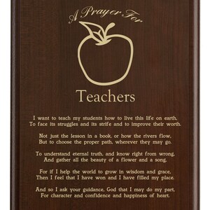 May include: A wooden plaque with a dark brown finish. The plaque features an apple graphic and the words "A Prayer For Teachers" in a decorative font. The plaque also includes a poem about teaching.