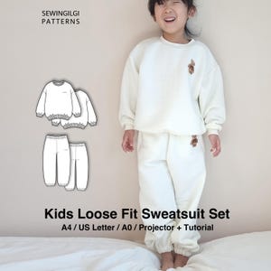 May include: A child in a cream-coloured, loose-fit sweatsuit with a teddy bear patch. The outfit includes a crew neck sweatshirt and matching trousers. The image also shows a pattern for the sweatsuit with the text "Kids Loose Fit Sweatsuit Set".