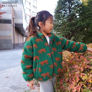 May include: A green fleece jacket with a repeating pattern of brown bear silhouettes, featuring a high collar, a full-length black front zip, and long sleeves. The text SEWINGILGI PATTERNS is visible in the upper left corner.