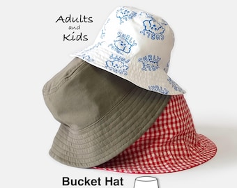 May include: Three bucket hats stacked together. The top hat is white with a blue repeating pattern of a curly-haired dog and the text 'CURLY PUPPY'. The middle hat is solid olive green. The bottom hat features a red and white gingham pattern.