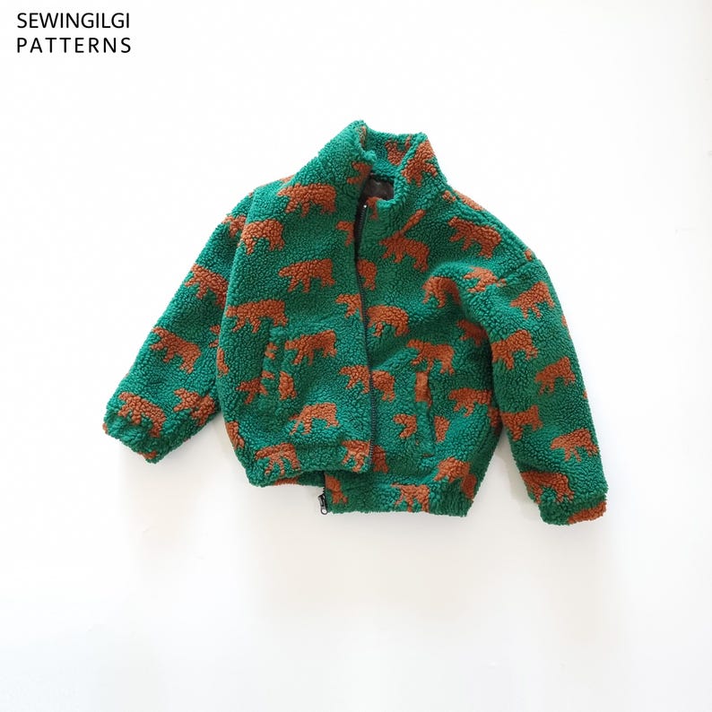 May include: A green zip-up jacket made of textured fleece material featuring a repeating pattern of brown bear silhouettes. The garment includes a high collar and long sleeves. The text SEWINGILGI PATTERNS is visible in the top left corner.