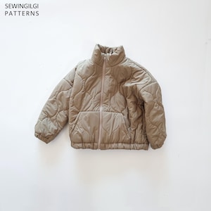 May include: A beige quilted jacket with a high collar, a full-length front zip, and long sleeves with elasticated cuffs. The jacket features a repeating curved pattern across the fabric and includes the text SEWINGILGI PATTERNS.