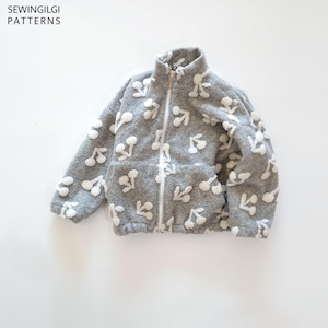 May include: A grey fleece zip-up jacket featuring a white cherry pattern, a high collar, and two front pockets. The text SEWINGILGI PATTERNS is visible in the top left corner. The jacket has a white zip closure and long sleeves.