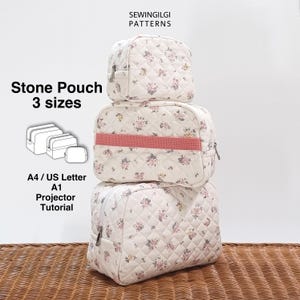 May include: Three quilted stone pouches in varying sizes are stacked. The pouches have a floral pattern on a cream background. The middle pouch has a pink band. Text on the image reads "Stone Pouch 3 sizes" and "Sewingilgi Patterns".
