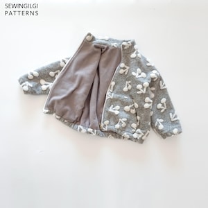 May include: A grey zip-up jacket featuring a white cherry pattern, a high collar, and a solid grey interior lining. The text SEWINGILGI PATTERNS is visible in the upper left corner of the image. The jacket has long sleeves and a hem.