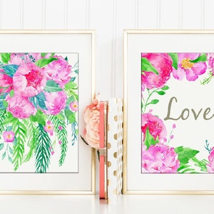 May include: Two framed watercolor prints with pink flowers and green leaves. The print on the left features a bouquet of pink peonies. The print on the right features a wreath of pink peonies with the word "Love" in the center.