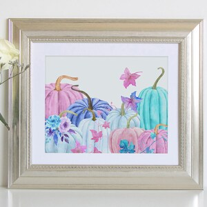 Pu&ograve; includere: Un dipinto ad acquerello di zucche color pastello con accenti floreali. Le zucche sono in tonalit&agrave; di rosa, blu e turchese, e i fiori sono in tonalit&agrave; di blu e viola. Il dipinto &egrave; incorniciato in una cornice argentata.