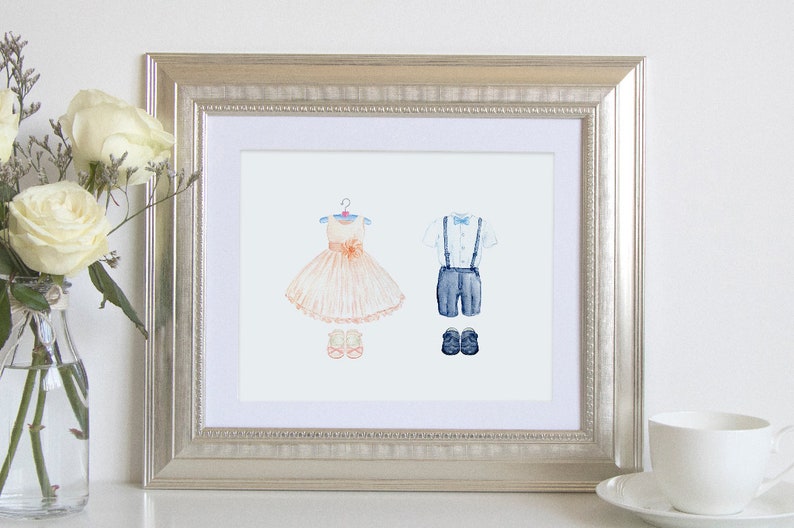 May include: A framed watercolor illustration of a girl's dress and a boy's outfit. The girl's dress is peach and white with a pink bow. The boy's outfit is blue and white with a bow tie. Both outfits are hanging on hangers.