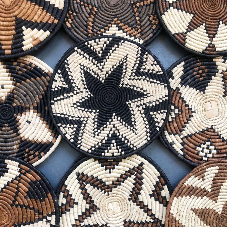 May include: A set of eight woven wall decor pieces in black and white with a geometric pattern. The pieces are made of natural materials and have a rustic, bohemian style.