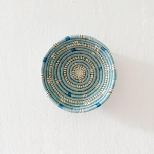 May include: A woven basket with a blue and white pattern. The basket is round and has a diameter of about 6 inches.