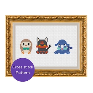 May include: A framed cross-stitch pattern showing three cartoon animal characters. The characters are a brown owl with a teal bow tie, a black and orange cat, and a blue seal. The frame is gold with ornate detailing. A purple circle with the text "Cross stitch Pattern" is in the lower left corner.