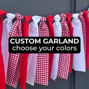Puede incluir: Una guirnalda de tela con tiras alternas de tela sólida roja y blanca y tela con patrón de cuadros vichy rojo y blanco atadas a una cuerda. El texto CUSTOM GARLAND choose your colors está impreso en blanco sobre un fondo negro.