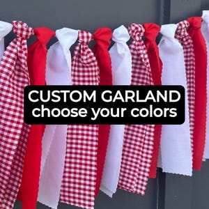 May include: A custom garland with red, white, and red and white checkered fabric strips. The text "CUSTOM GARLAND choose your colors" is displayed on a black background. The garland is hanging against a dark background.