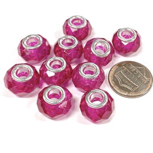 May include: Ten fuchsia pink glass beads with silver metal accents. The beads have a faceted design and are approximately the size of a US penny.