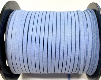 May include: A spool of light blue suede cord, wound tightly around a black plastic spool. The cord is smooth and has a slightly textured surface.