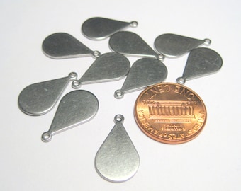 Könnte beinhalten: Eine Sammlung kleiner, silberfarbener, tropfenförmiger Metallanhänger mit einer kleinen Schlaufe oben zum Befestigen an Schmuck. Eine Münze dient zum Größenvergleich. Die Anhänger haben eine gebürstete Metalloberfläche.