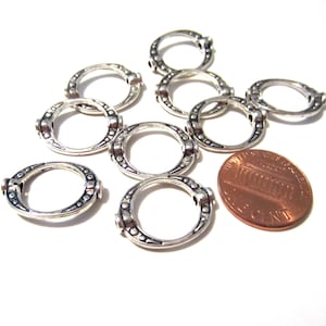 Könnte beinhalten: Zehn silberfarbene Metallringe mit dekorativem Design. Die Ringe sind etwa so groß wie ein Cent-Stück.