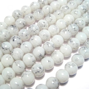 May include: White glass beads with black marbling. The beads are round and have a smooth, glossy finish.