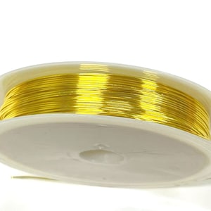 May include: A spool of gold-colored wire on a white plastic spool.