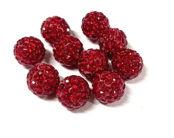 May include: A group of ten red rhinestone beads. The beads are round and have a textured surface.