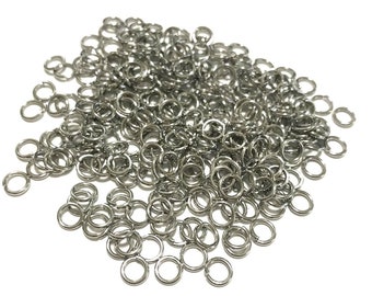 May include: A large pile of silver jump rings. The rings are small and round, and they are all linked together.
