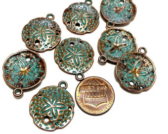 May include: A collection of eight copper-toned metal charms shaped like sand dollars with a turquoise blue enamel finish. Each charm has a five-pointed star design in the center and a hole for attaching a jump ring.