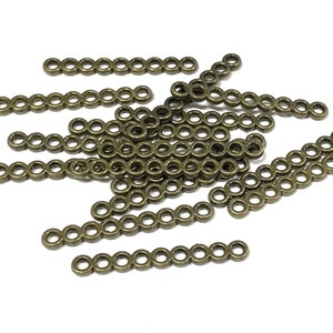 May include: A pile of antique gold metal chain links, each link is a circle, and the links are connected in a row to form a chain. The chains are about 1 inch long.