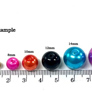 May include: Size example of round plastic beads in various colors and sizes, measured on a ruler in millimeters. The beads range in size from 4mm to 16mm.