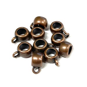 May include: Ten antique copper-toned metal bead caps with a loop on one end. The caps are designed to be used as end caps for necklaces, bracelets, or other jewelry projects.