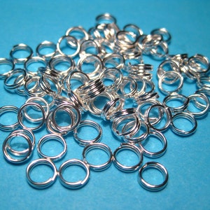 May include: A pile of silver jump rings, a type of jewelry finding, on a blue background.