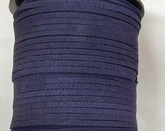 May include: A spool of dark blue suede cord, wound tightly on a black plastic spool.