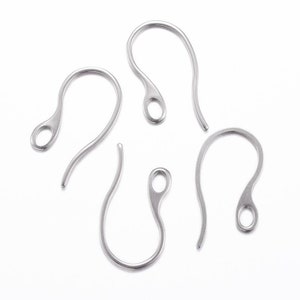 May include: Five silver earring hooks, also known as French hooks, are shown on a white background. The hooks are made of metal and have a loop at the top for attaching earrings.