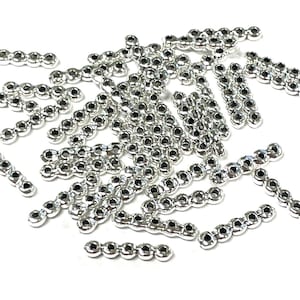 May include: A large pile of silver-toned metal spacer beads. Each bead is a cylinder with multiple small circles along its length.