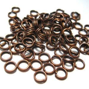 May include: A pile of small, copper-colored jump rings. The rings are about 6mm in diameter and are perfect for jewelry making.
